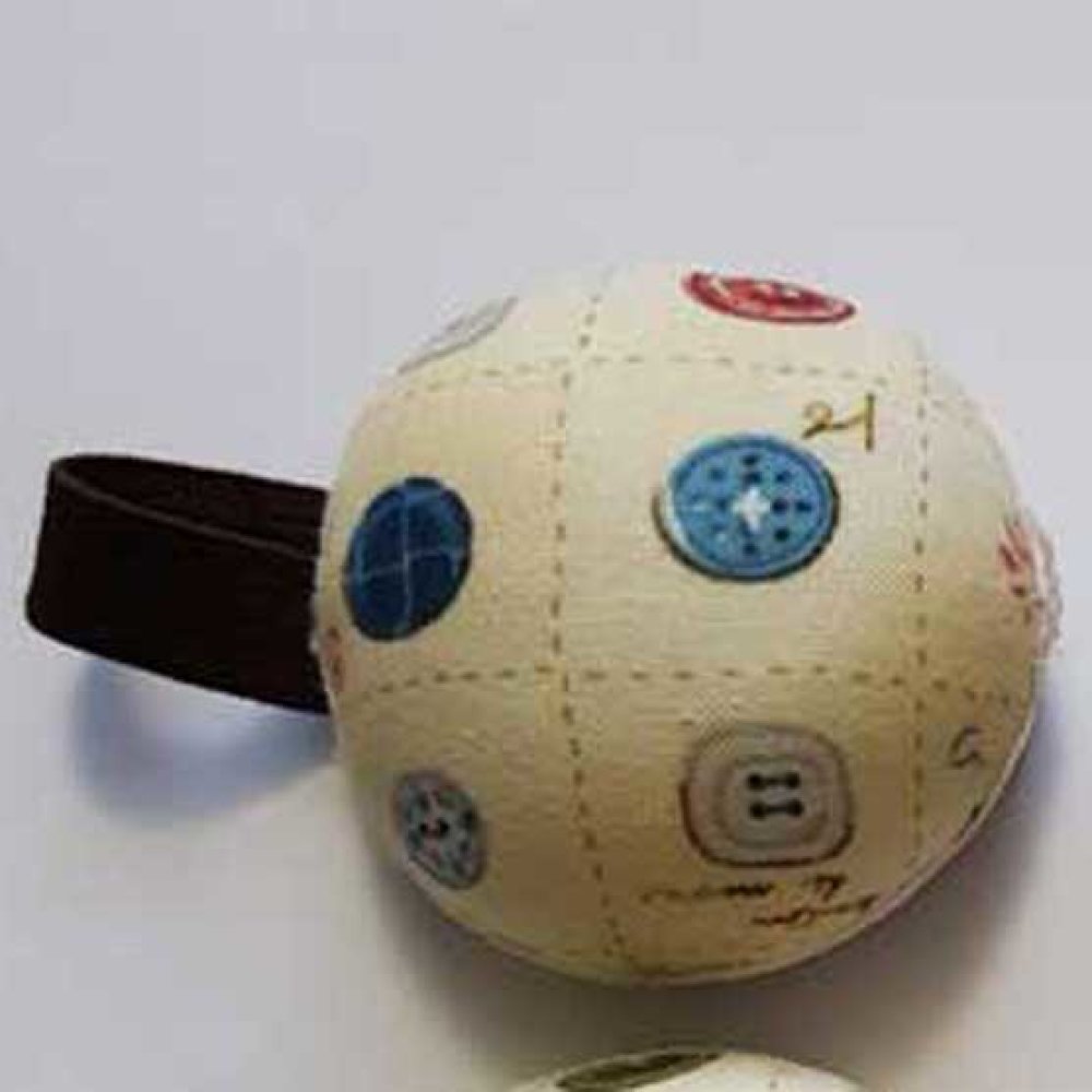 Bracelet porte-épingles rond avec motif de boutons de couture.