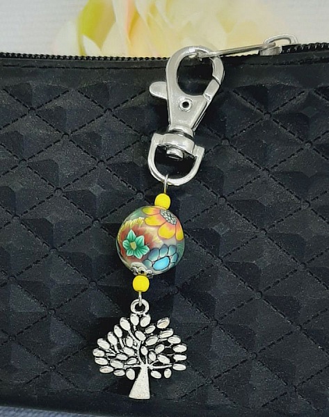 Porte-clé argenté avec arbre de vie et perle multicolore.