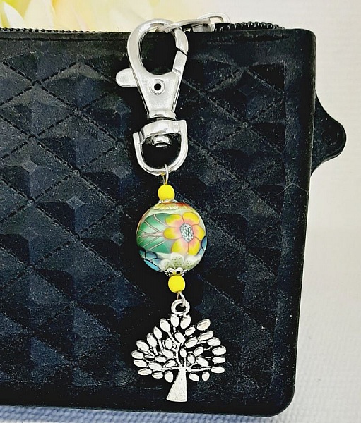 Porte-clé argenté avec arbre de vie et perle multicolore.