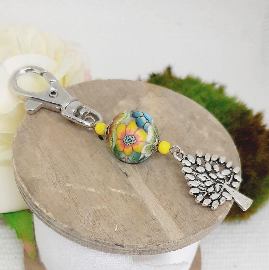 Porte-clé argenté avec arbre de vie et perle multicolore.