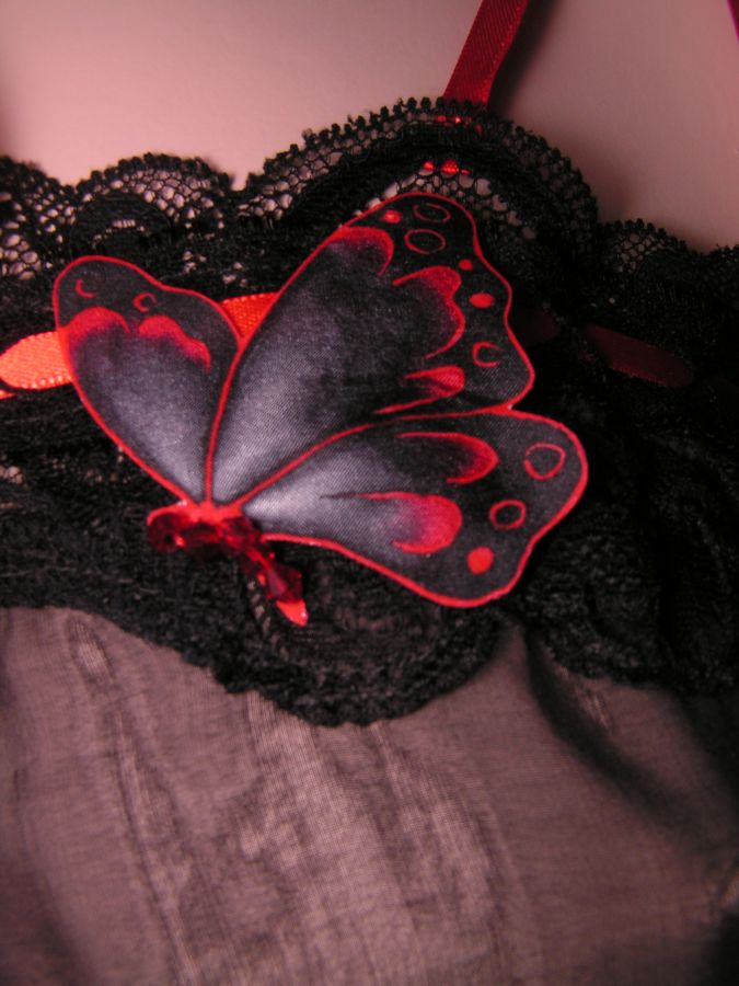 Déshabillé noir en soie avec détail papillon rouge.