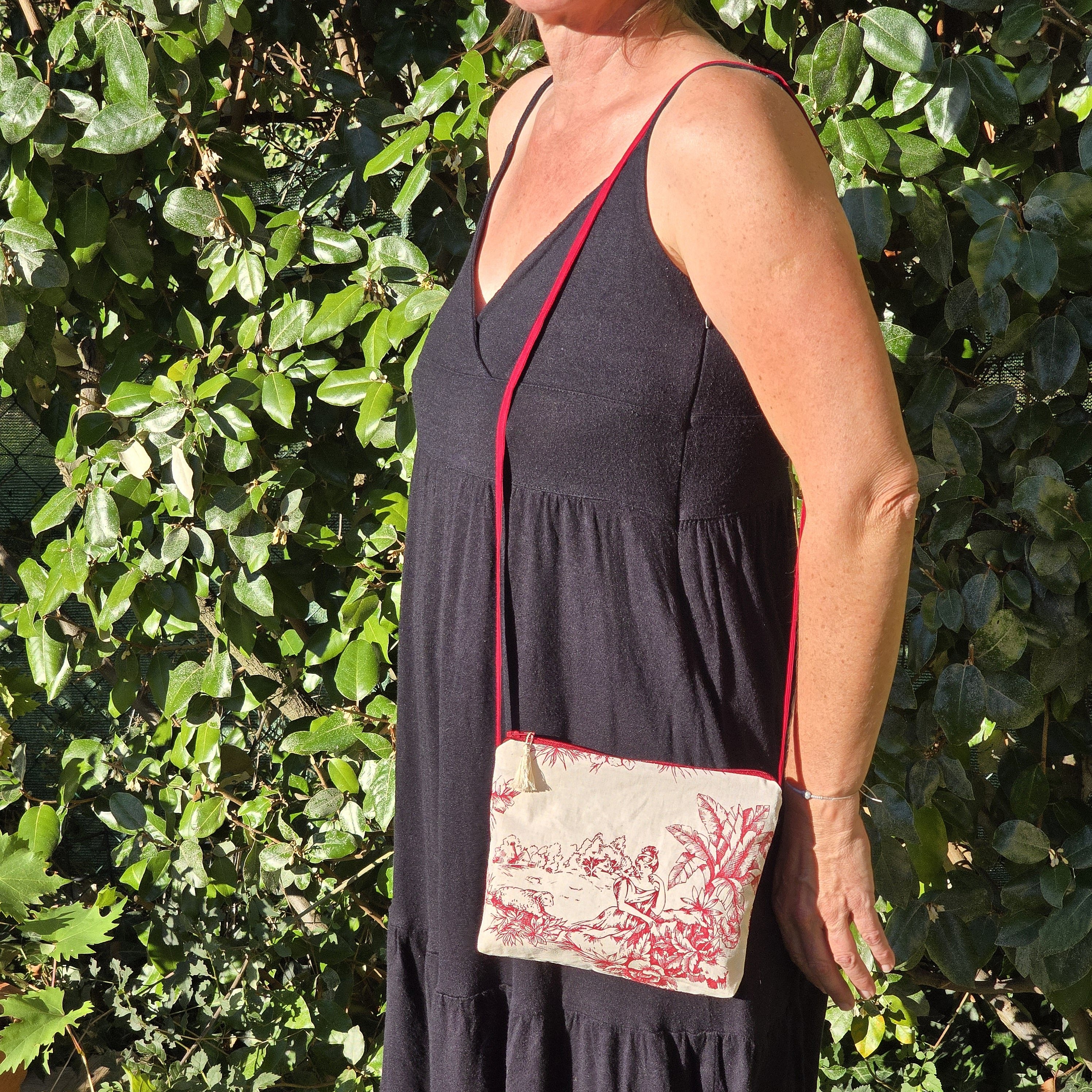 Pochette avec bandouli&egrave;re en tissu toile de Jouy bordeaux et &eacute;cru agr&eacute;ment&eacute;e d'un pompon