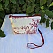 Pochette avec bandouli&egrave;re en tissu toile de Jouy bordeaux et &eacute;cru agr&eacute;ment&eacute;e d'un pompon