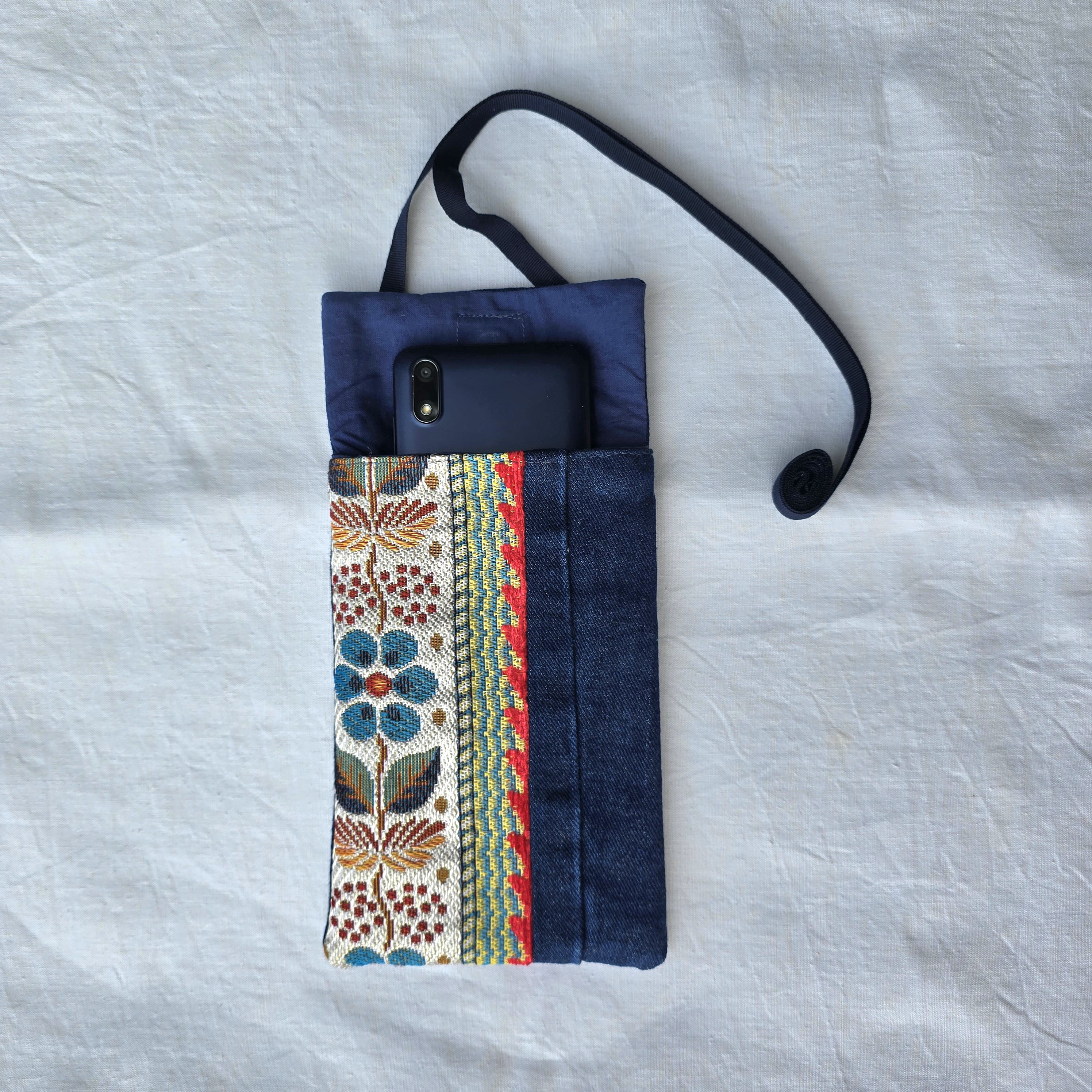 Pochette téléphone en jean recyclé avec bandoulière et motif floral.