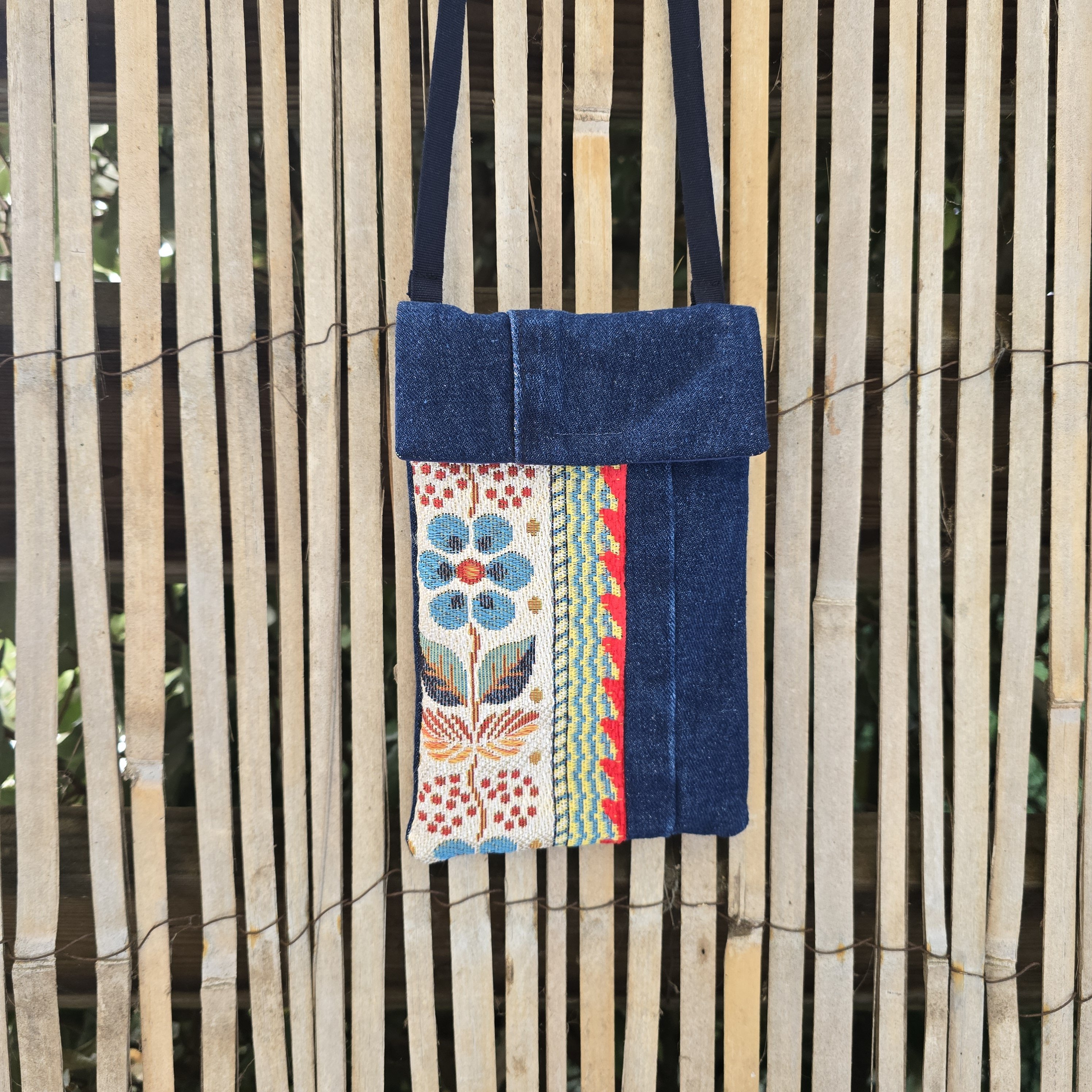 Pochette téléphone en jean recyclé avec bandoulière et motif floral.