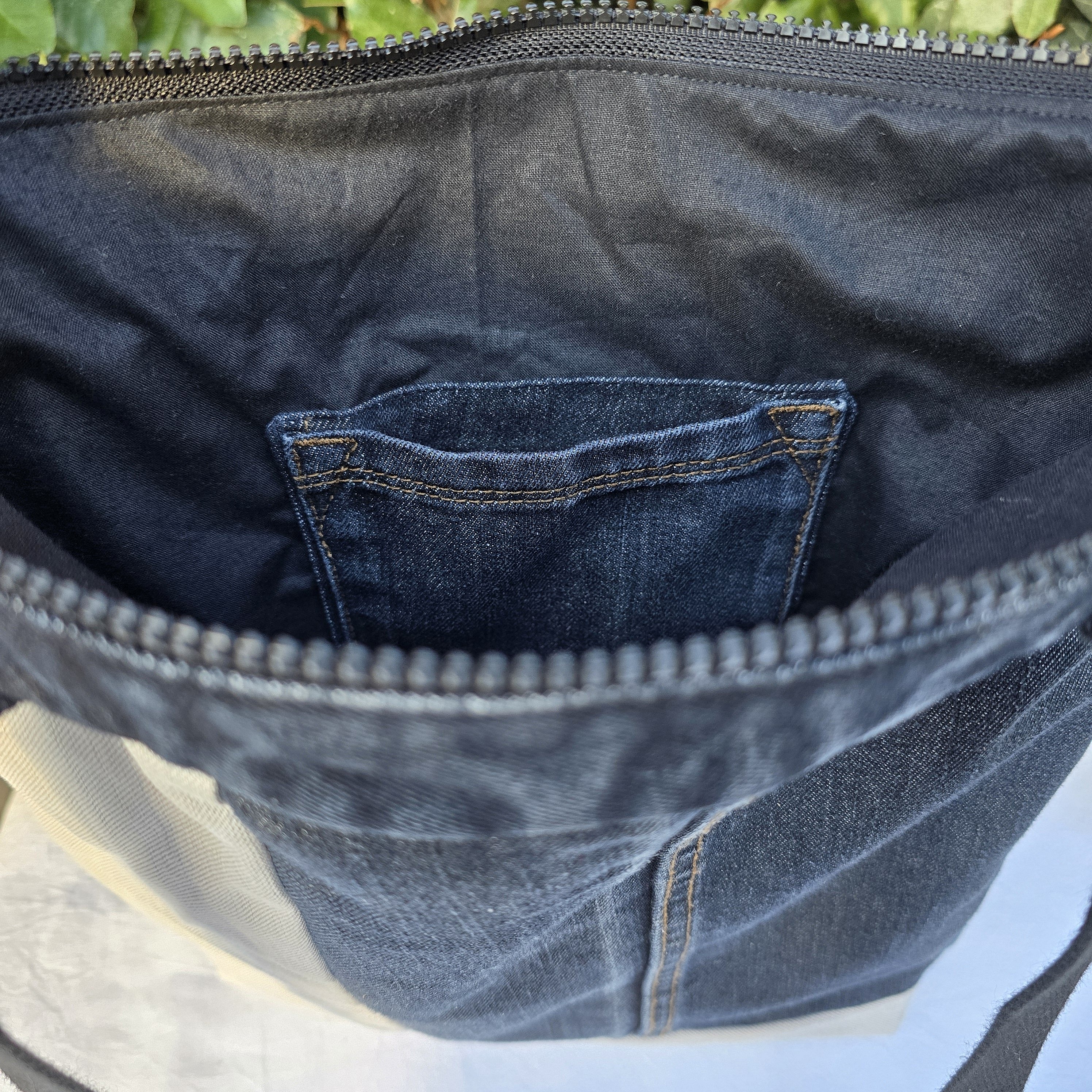 Intérieur d'un sac à bandoulière en jean recyclé avec poche.
