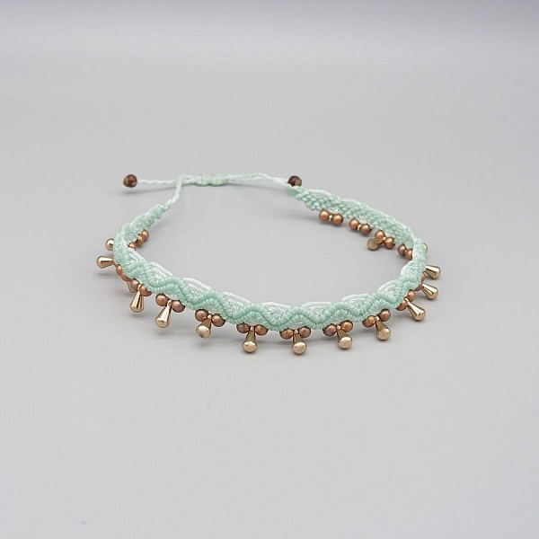 Bracelet de cheville en micro-macramé vert menthe à perles dorées.