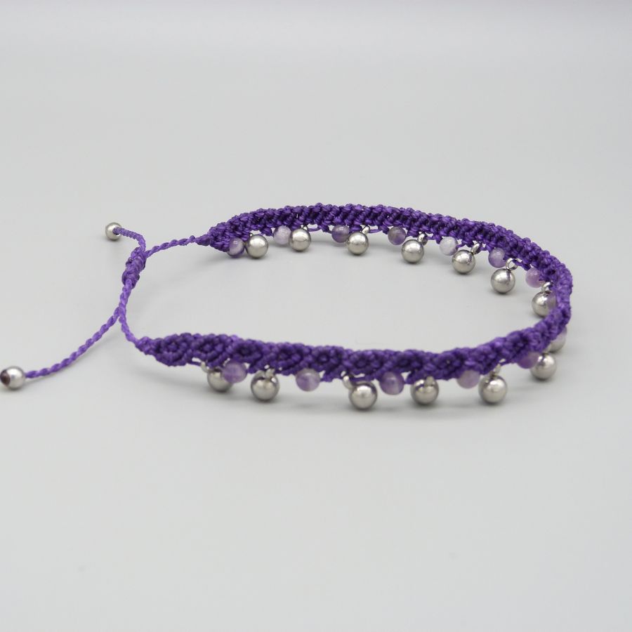 Bracelet de cheville en micro-macramé violet avec perles argentées.