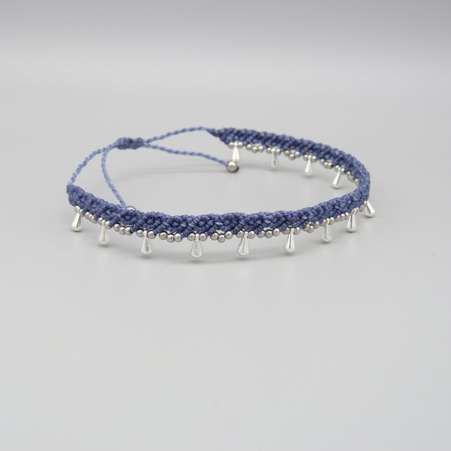 Bracelet de cheville en micro-macramé bleu avec perles argentées.