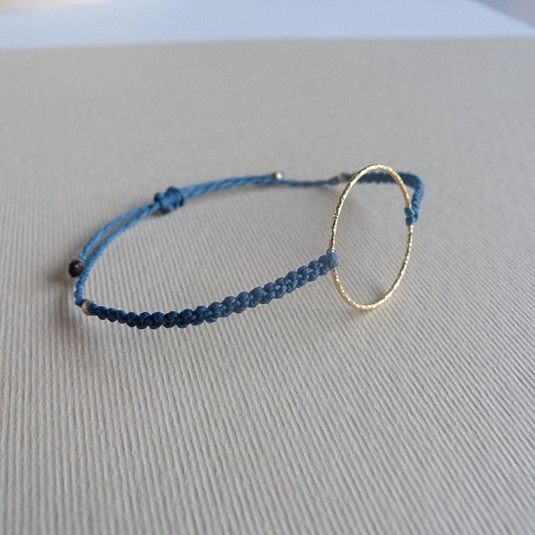 Bracelet fin en micro-macramé bleu avec anneau doré.