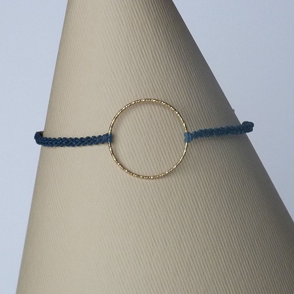 Bracelet fin en micro-macramé bleu avec anneau doré.