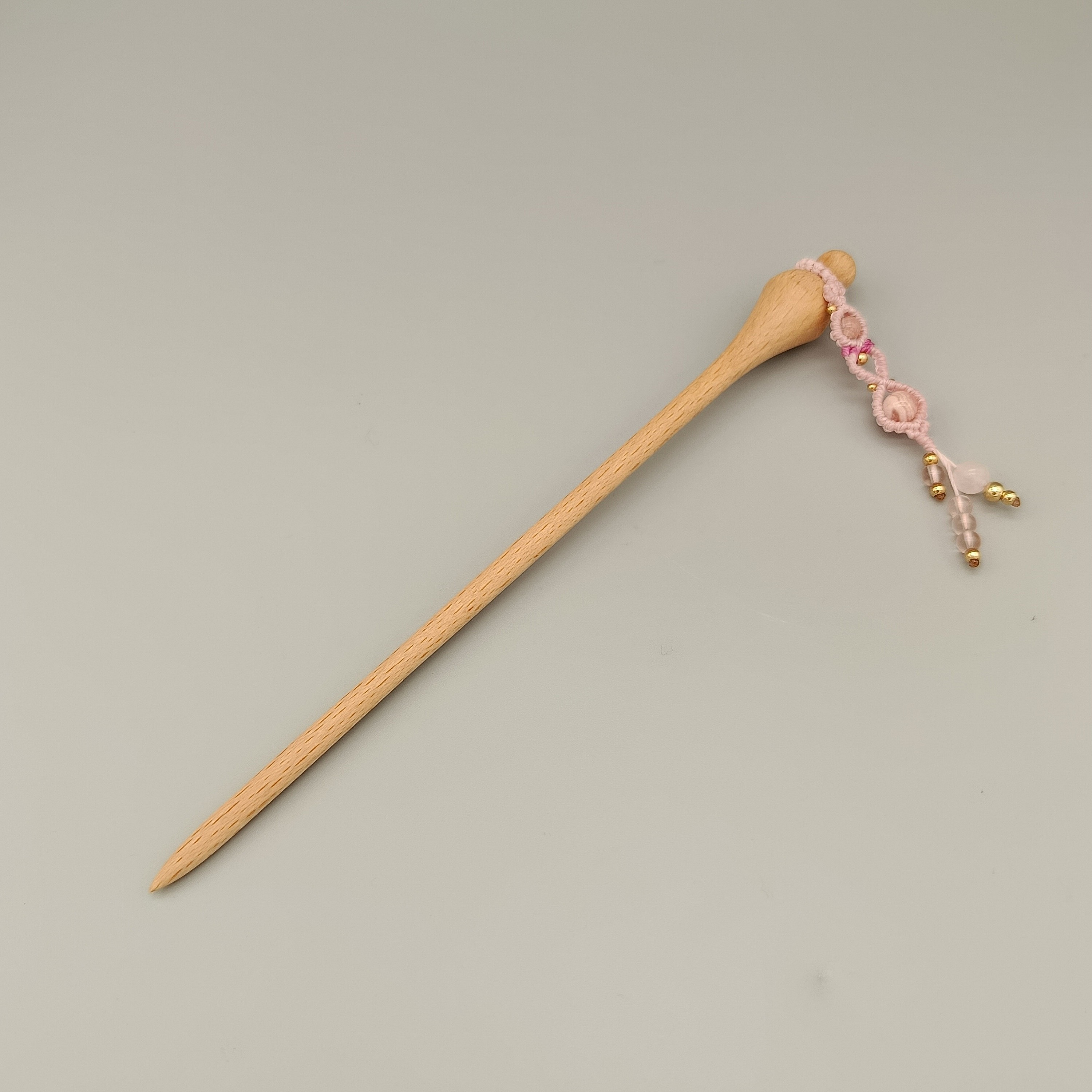 Pic à cheveux en hêtre avec ornement micro-macramé rose.