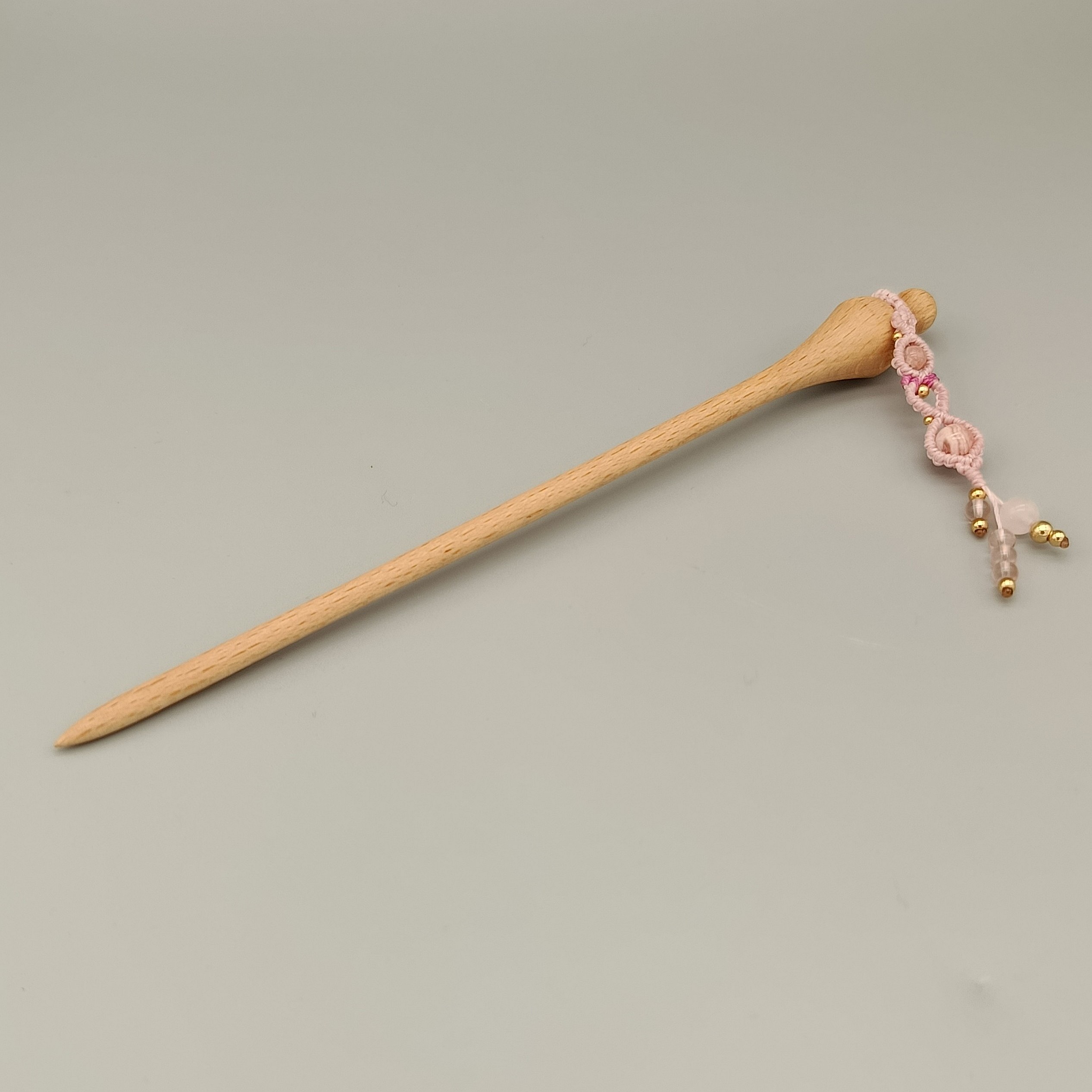 Pic à cheveux en hêtre avec ornement micro-macramé rose.