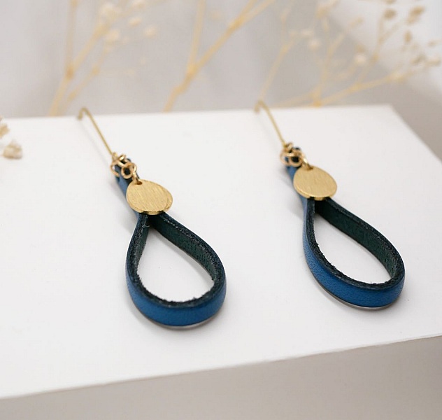 Boucles d'oreilles pendantes en cuir bleu et pampilles dorées.