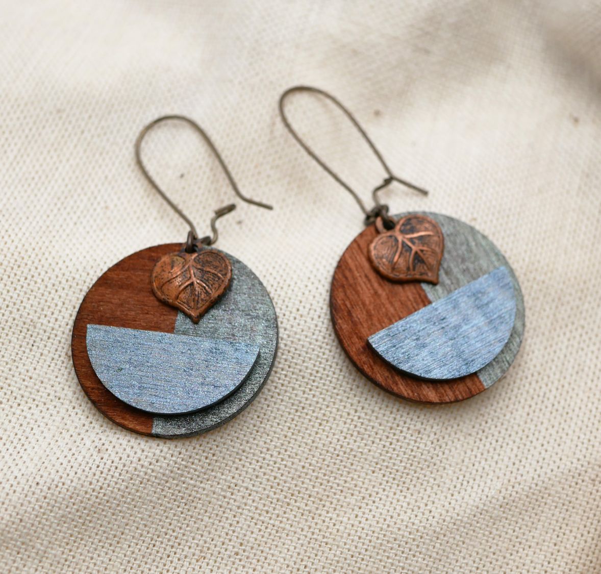 Boucles d'oreilles graphiques en bois avec pendentif feuille cuivrée.