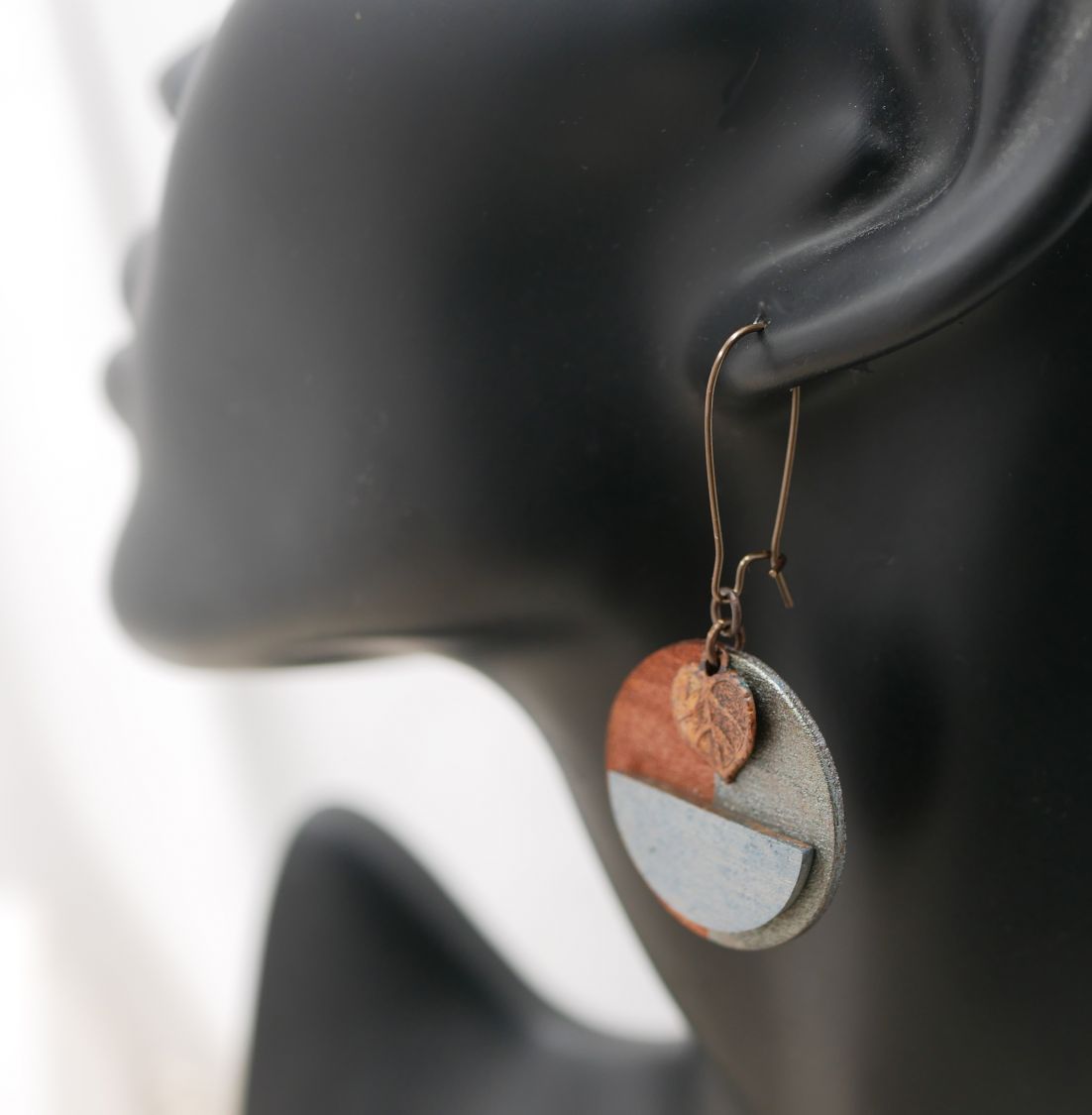 Boucles d'oreilles graphiques rondes en bois et feuille cuivrée.