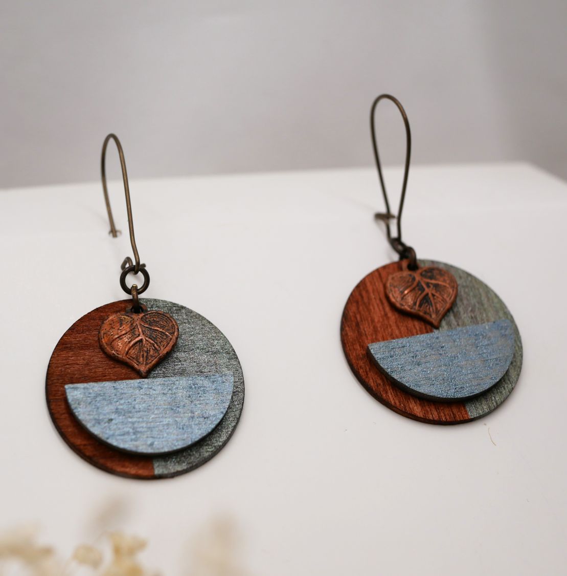 Boucles d'oreilles graphiques en bois avec pendentif feuille cuivrée.