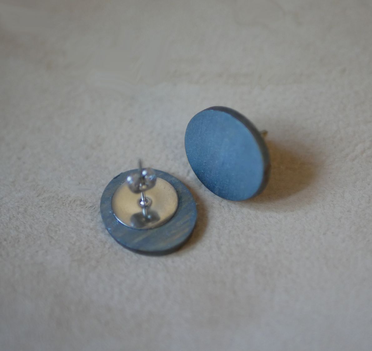 Puces d'oreilles ovales en bois peint gris effet métallisé.