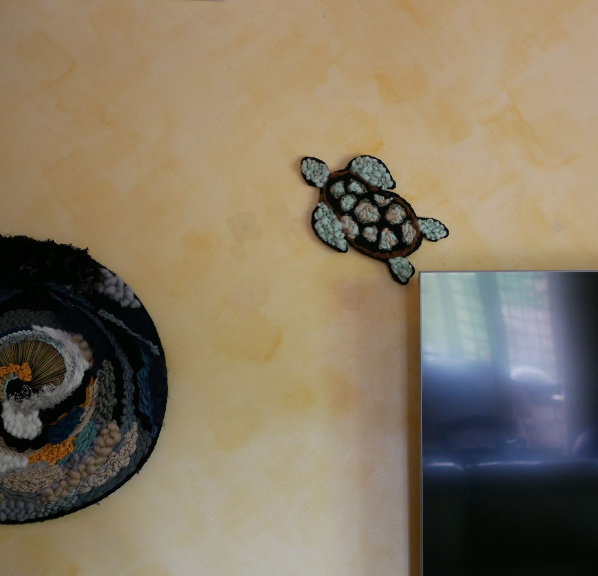 Décoration murale tortue artisanale en tissage de laine colorée.