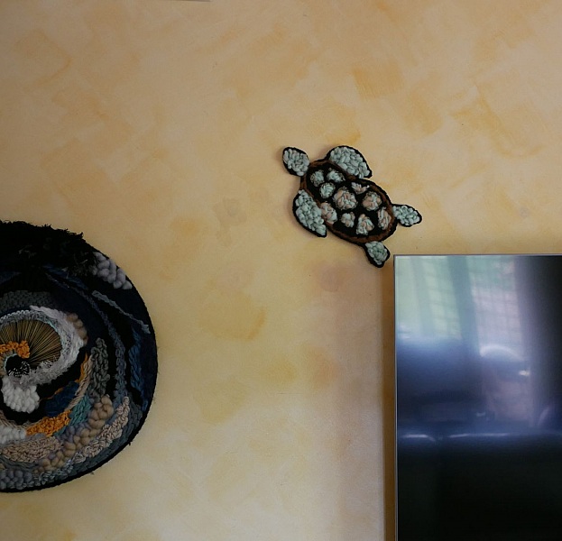 Décoration murale tortue artisanale en tissage de laine colorée.