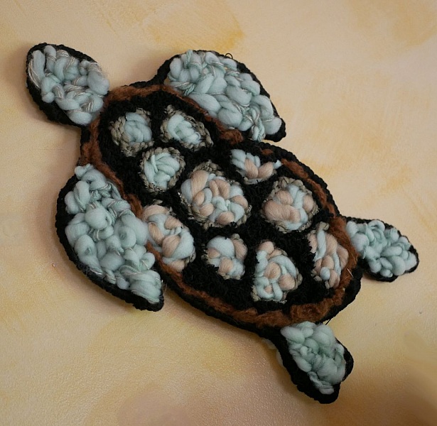 Décoration murale tortue artisanale en tissage de laine colorée.