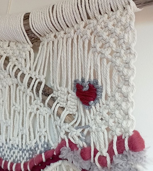 Suspension murale artisanale en macramé avec tissage coloré.