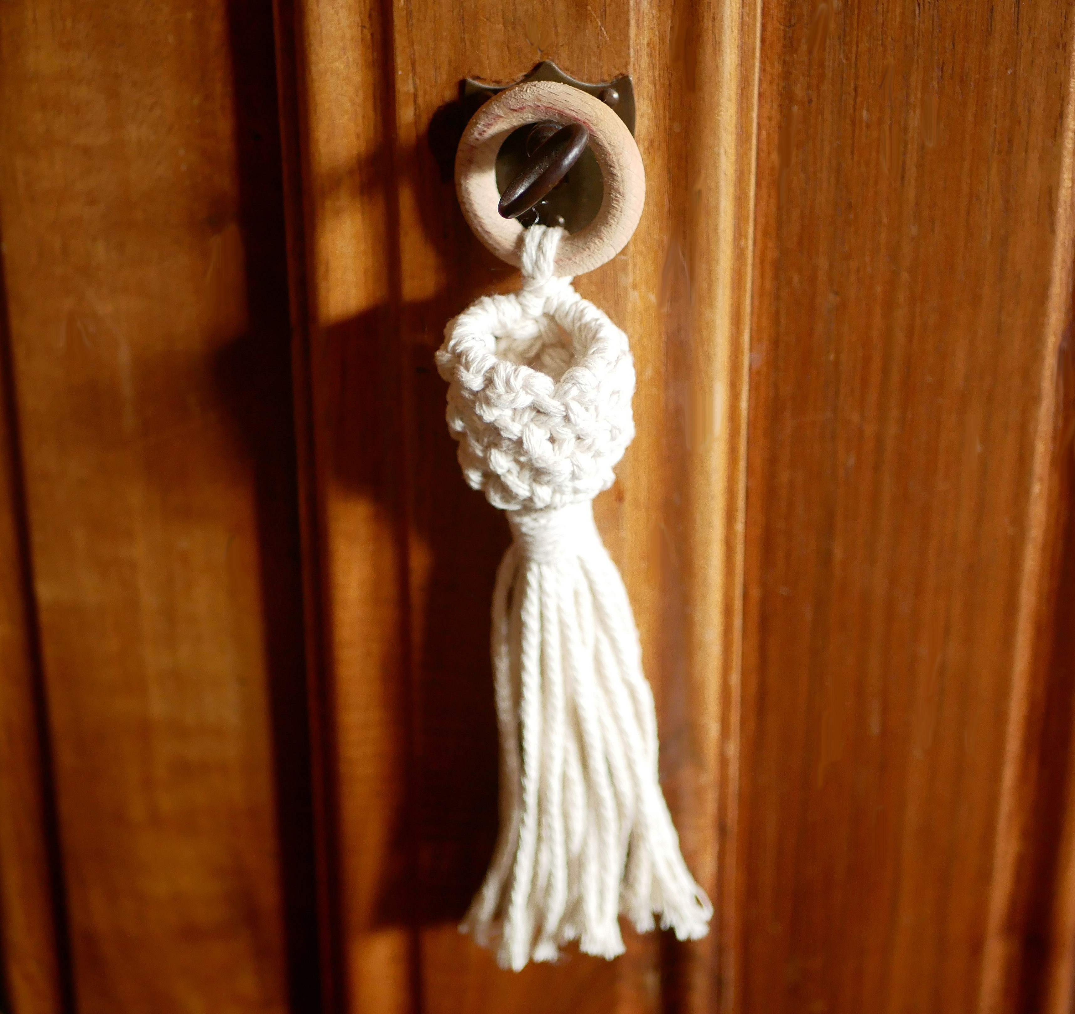 Mini suspension pour plante en macramé écru sur porte.
