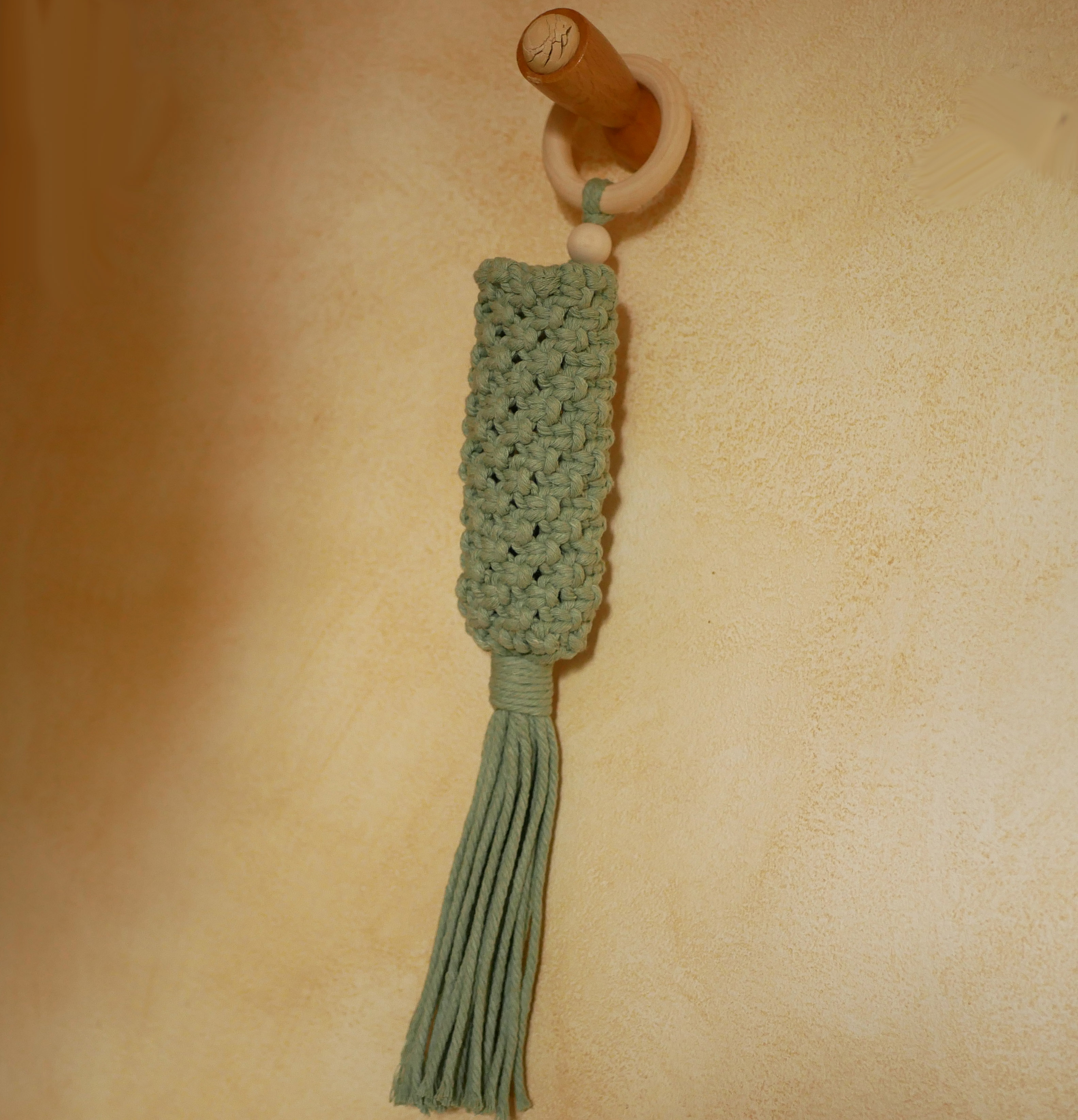 Suspension en macramé vert céladon avec anneau en bois.