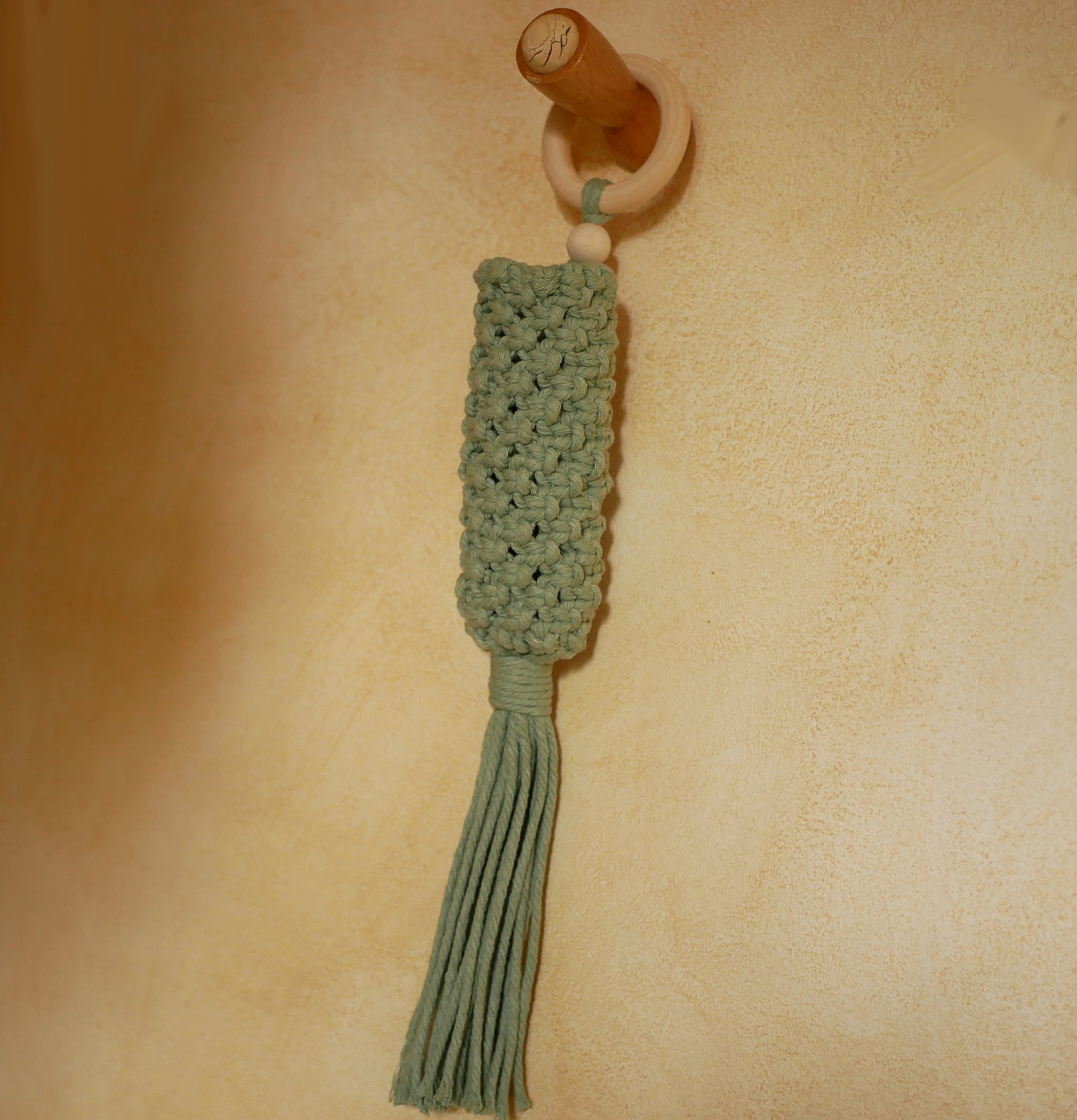 Suspension en macramé vert céladon avec anneau en bois.