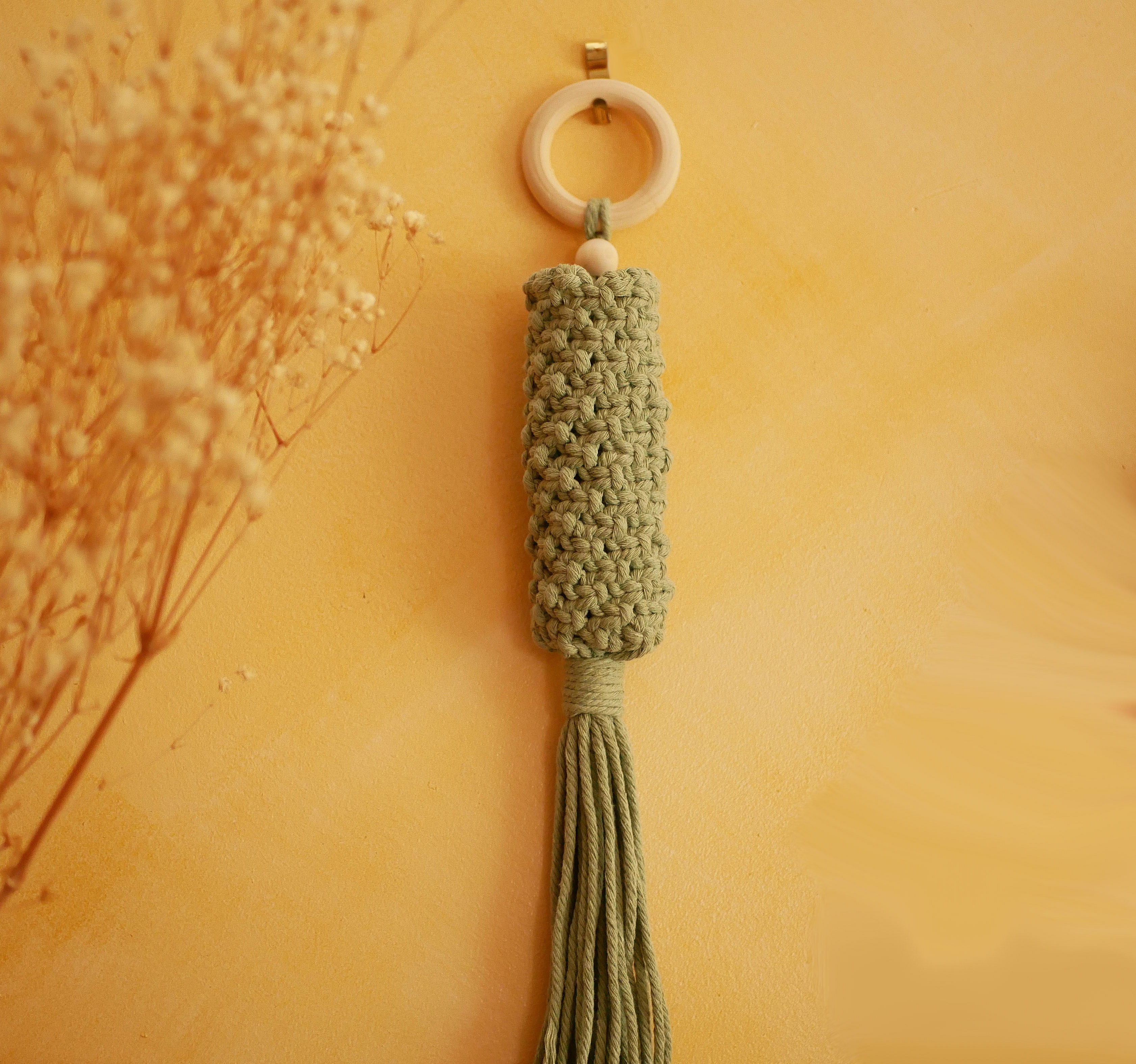Suspension murale en macramé vert céladon pour fleurs séchées.