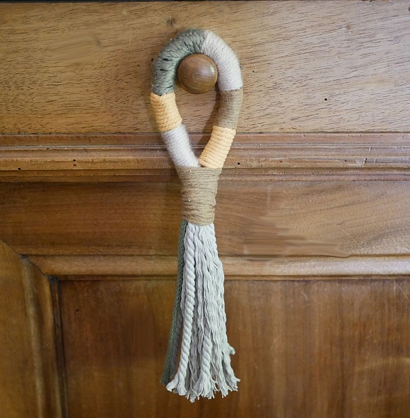 Suspension pompon en macramé pour poignée de porte en bois.