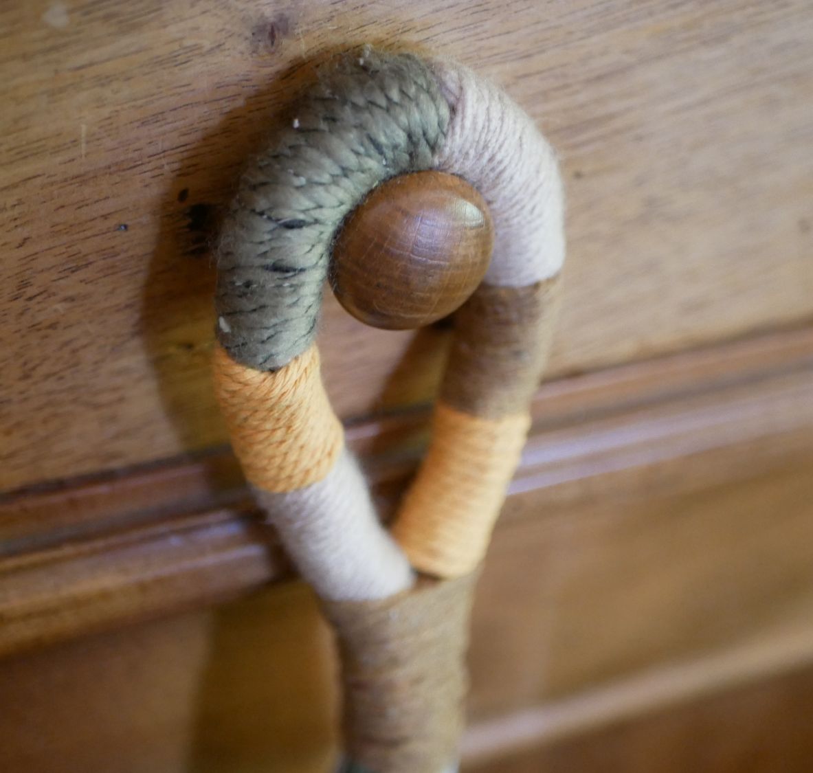 Suspension en macramé coloré pour poignée de porte en bois.