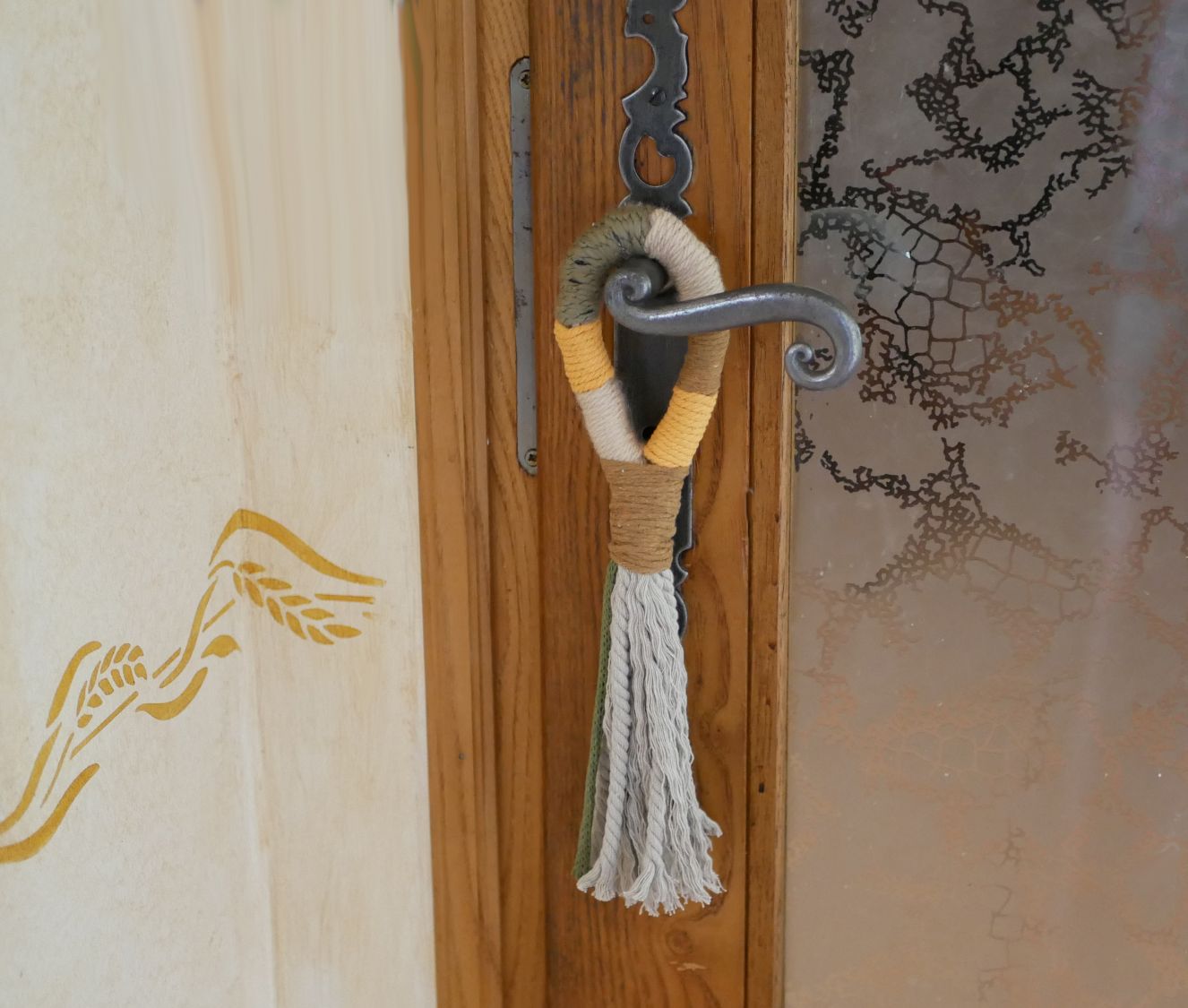 Suspension pompon en macramé décorant une poignée de porte.