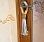 Suspension pompon en macramé décorant une poignée de porte.