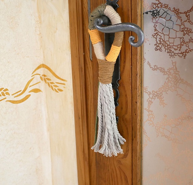 Suspension pompon en macramé décorant une poignée de porte.