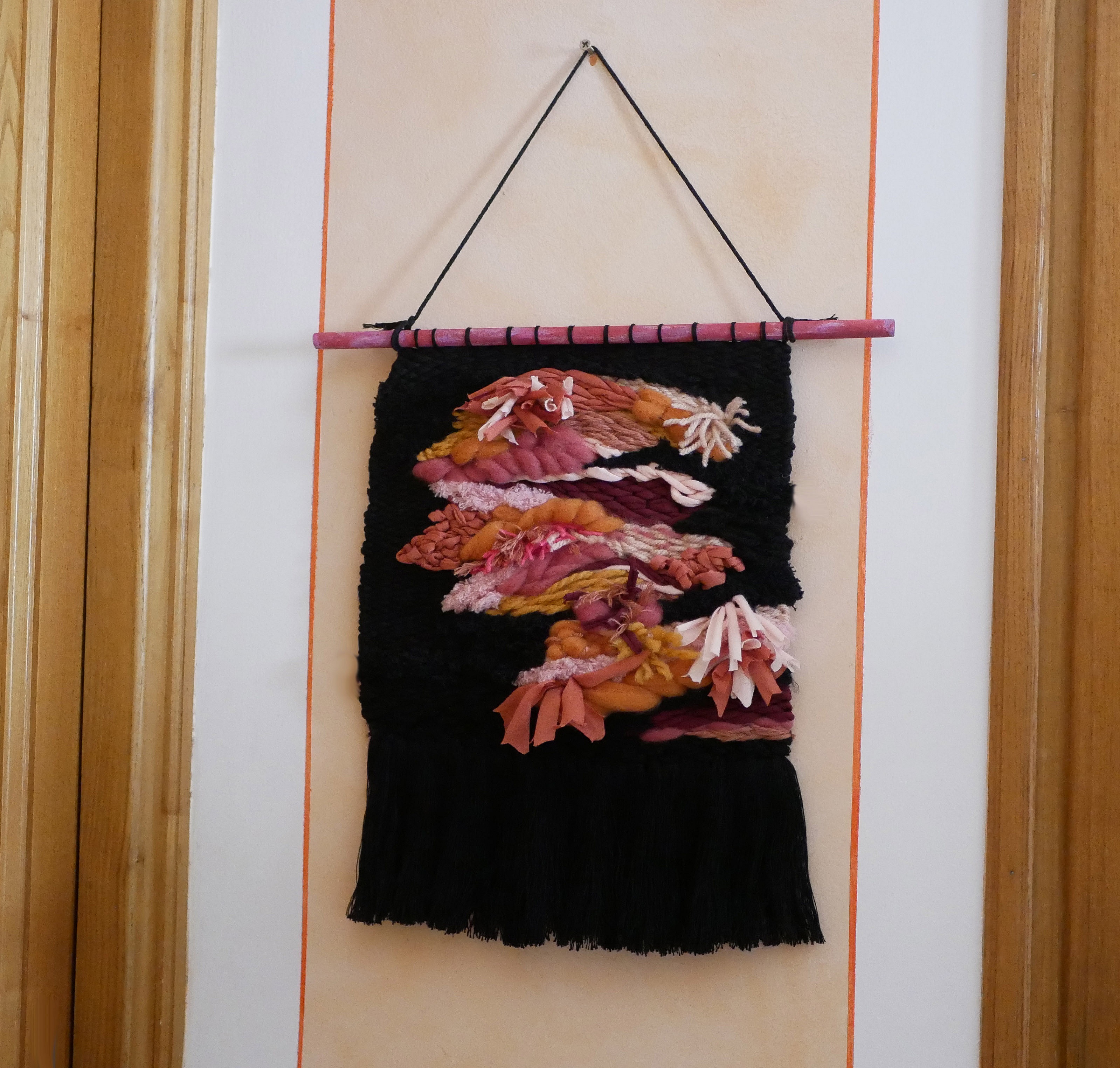 Tenture murale tissée à la main aux motifs floraux roses.