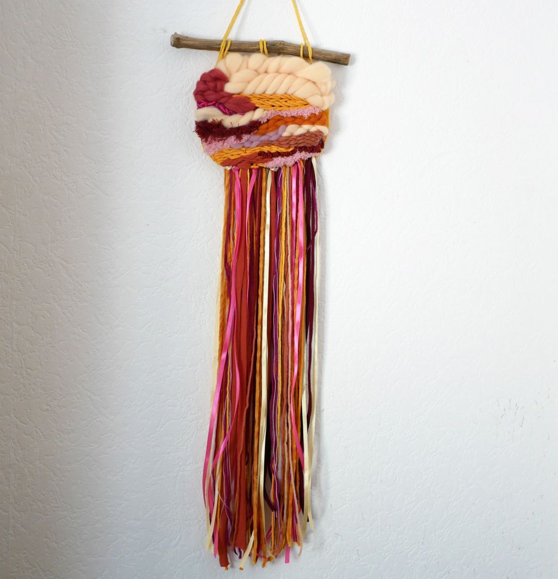 Suspension murale en laine aux couleurs vives et longues franges.