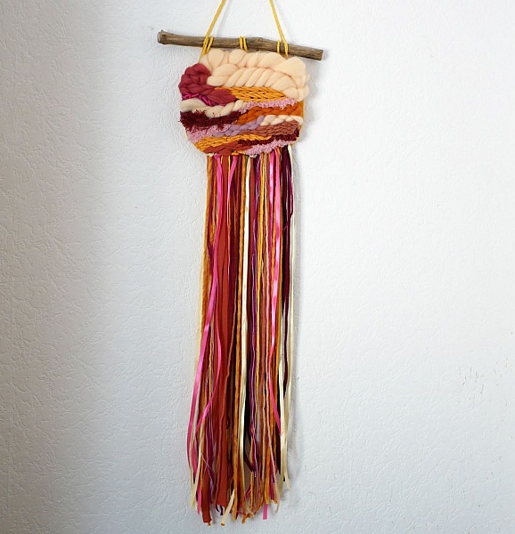Suspension murale en laine aux couleurs vives et longues franges.