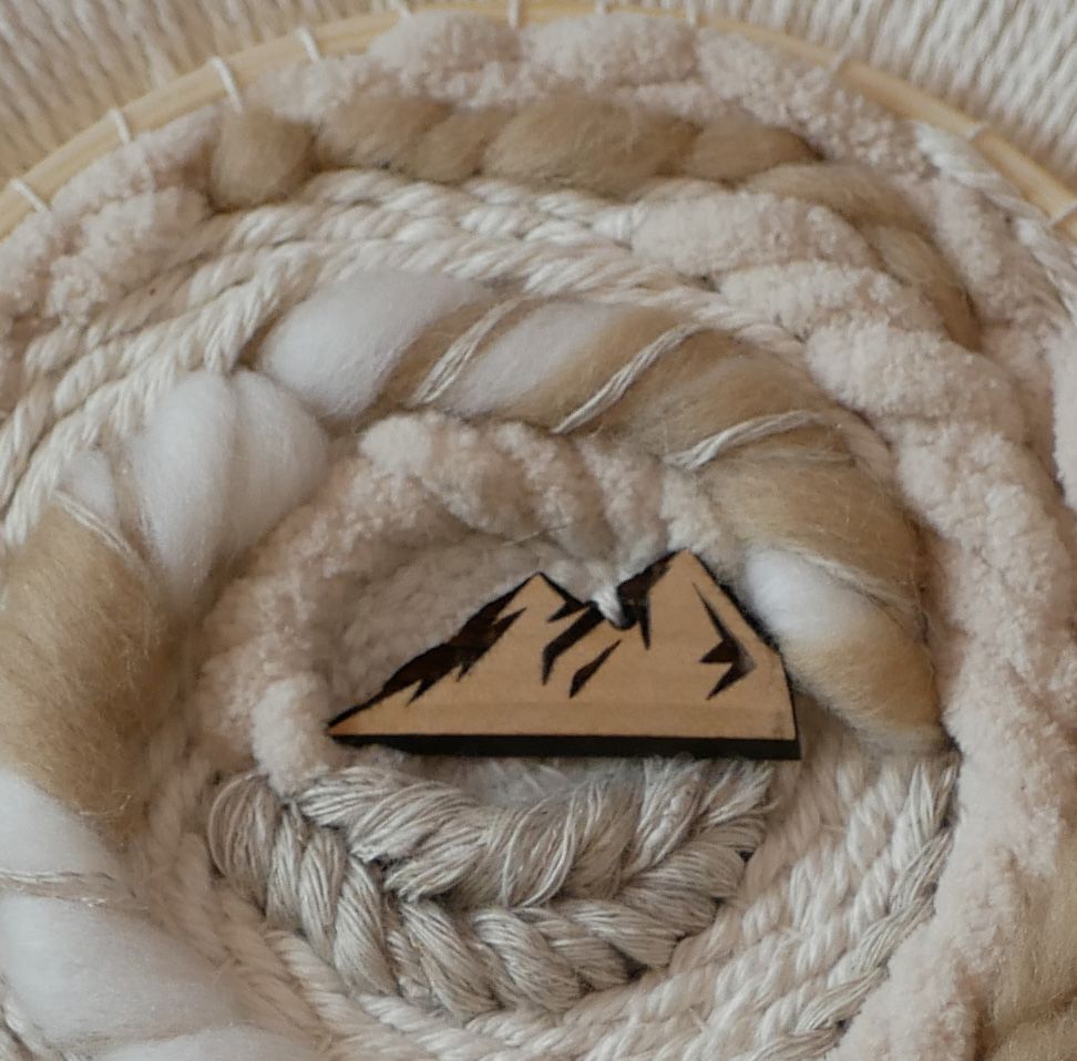 Tissage mural rond en macramé avec motif montagne en bois.