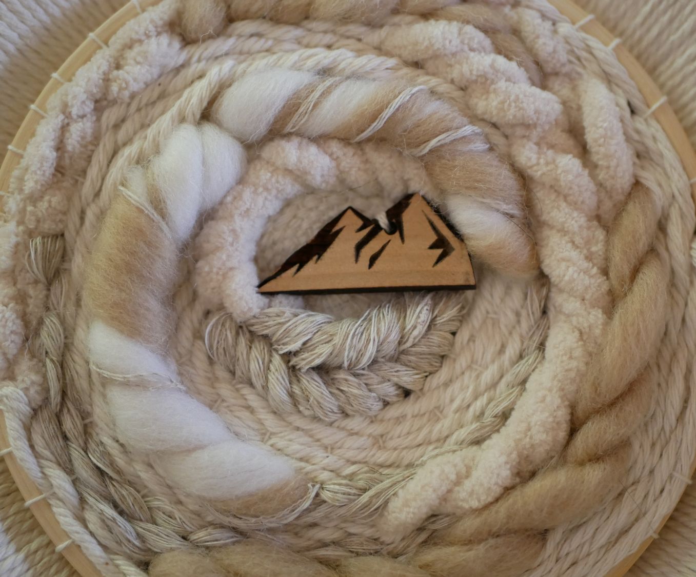 Tissage mural rond en macramé avec décor montagne en bois.