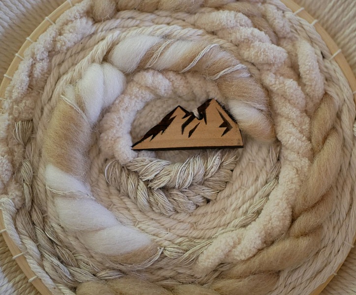 Tissage mural rond en macramé avec décor montagne en bois.