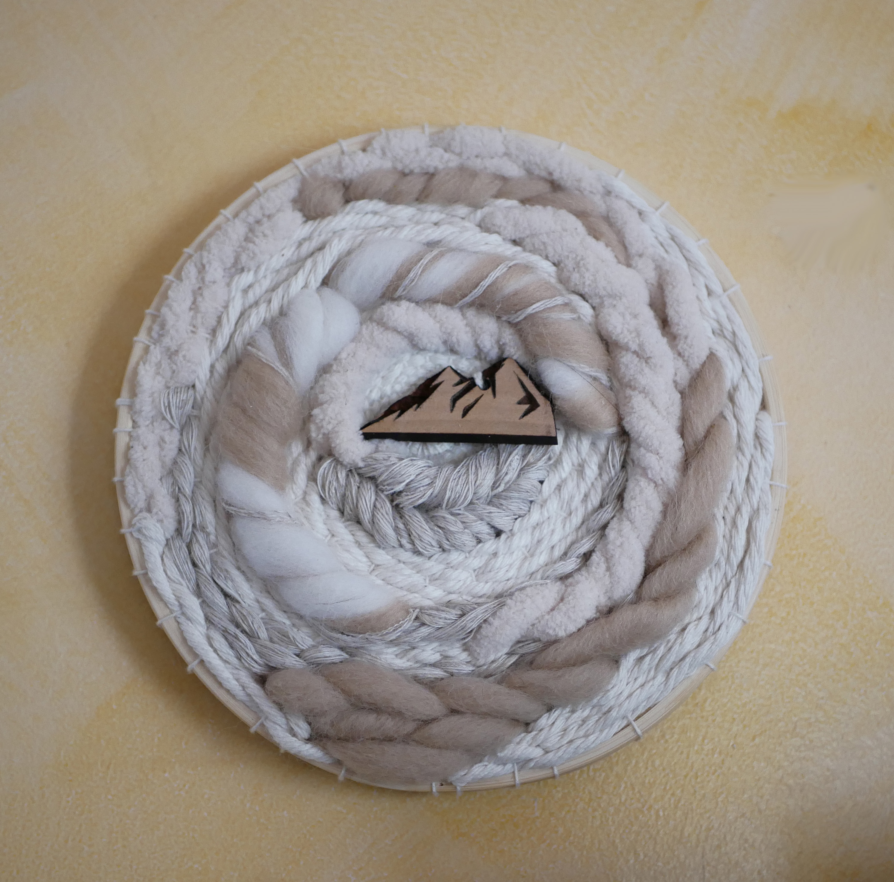 Tissage mural rond en macramé avec motif montagne en laine.