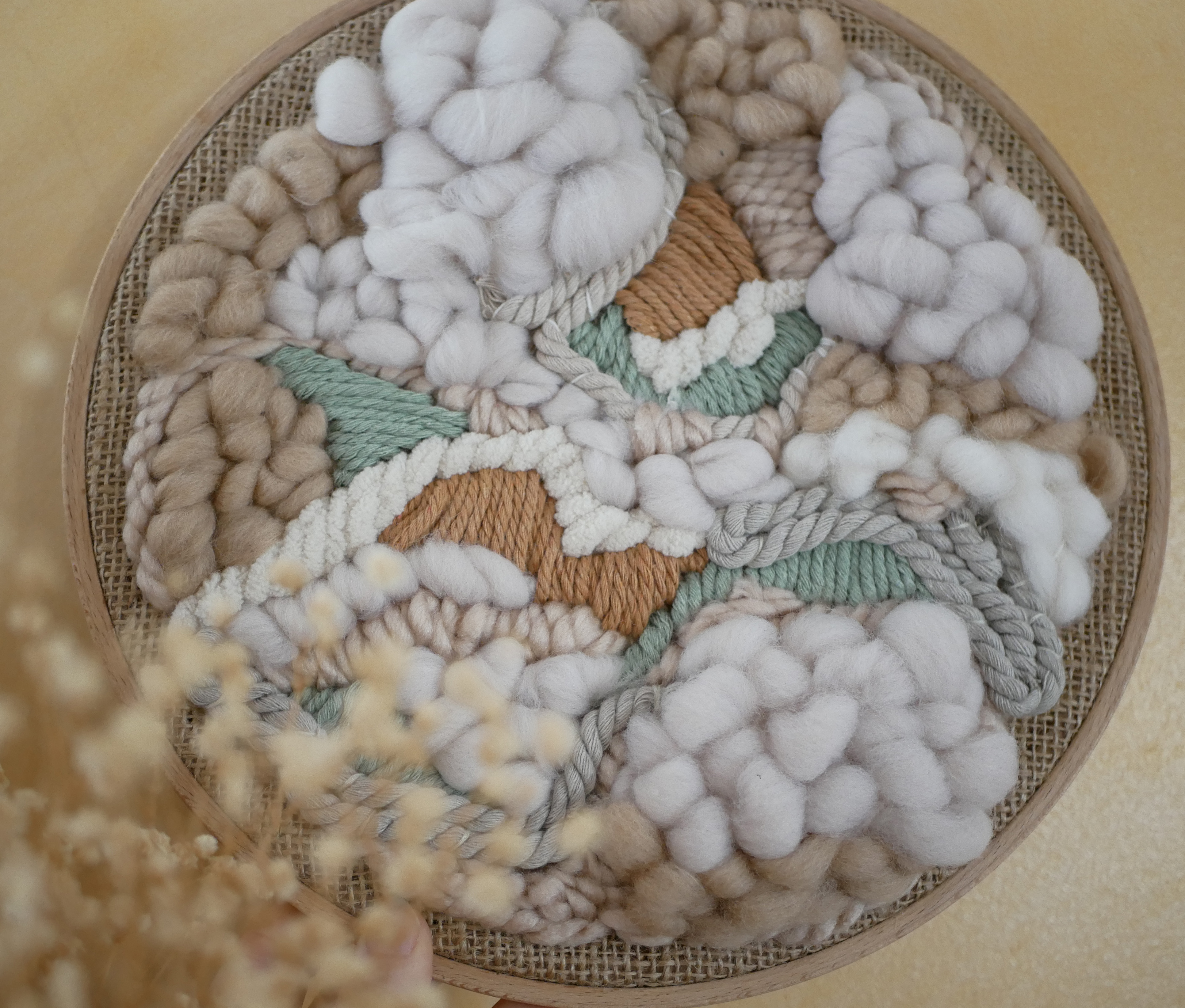 Tissage mural rond en laine et macramé tons neutres.