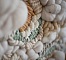 Gros plan sur un tissage mural artisanal en laine beige.
