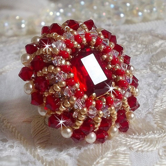 Bague Rubis brod&eacute;e avec un cabochon rectangulaire Ruby, orn&eacute;e de chatons mont&eacute;s en Cristal avec des perles rondes nacr&eacute;es en verre Ivoire, rocailles Dor&eacute;es, des toupies Cristal AB et Burgundy.