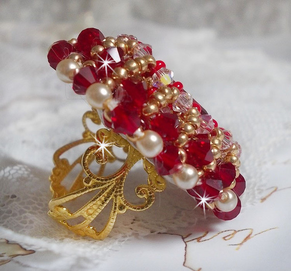 Bague Rubis brod&eacute;e avec un cabochon rectangulaire Ruby, orn&eacute;e de chatons mont&eacute;s en Cristal avec des perles rondes nacr&eacute;es en verre Ivoire, rocailles Dor&eacute;es, des toupies Cristal AB et Burgundy.
