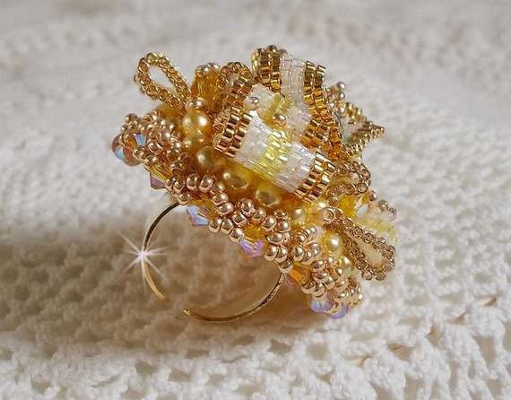 Bague Sunflower Gold brod&eacute;e d&rsquo;un ruban que j&rsquo;ai mis en forme avec des rocailles plaqu&eacute;es or 24 carats, perles nacr&eacute;es en cristal, toupies, perle ronde nacr&eacute;e. Le tout est mont&eacute; sur une bague Dor&eacute;e