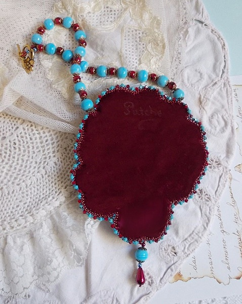 Dos d'un collier brodé en suédine bordeaux et perles.