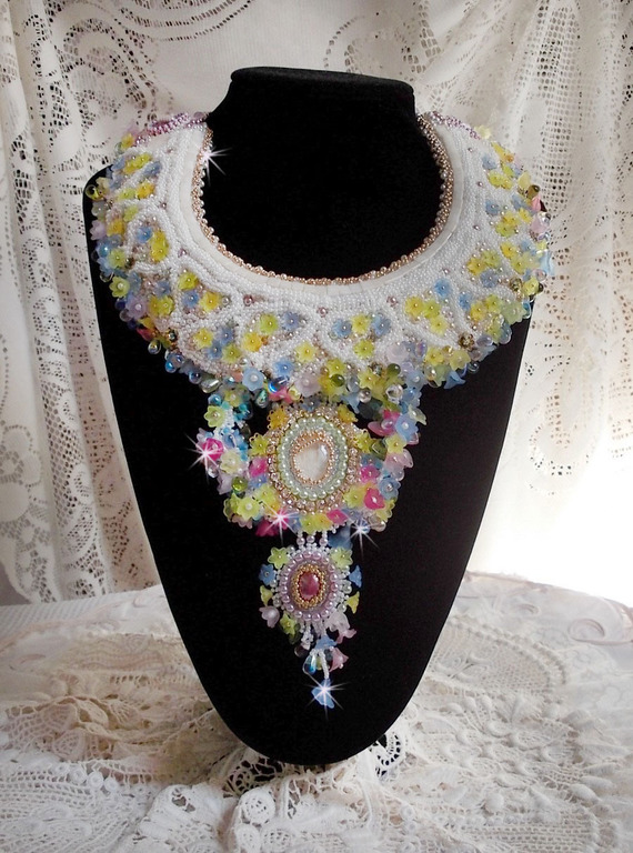 Plastron Envol&eacute;e Fleurie Haute Couture brod&eacute; avec des cabochons Nacre et R&eacute;sine aux couleurs Fuchsia et Ivoire, s&rsquo;ajoute des fleurs lucites, feuilles en verre, chatons et perles en Cristal.
