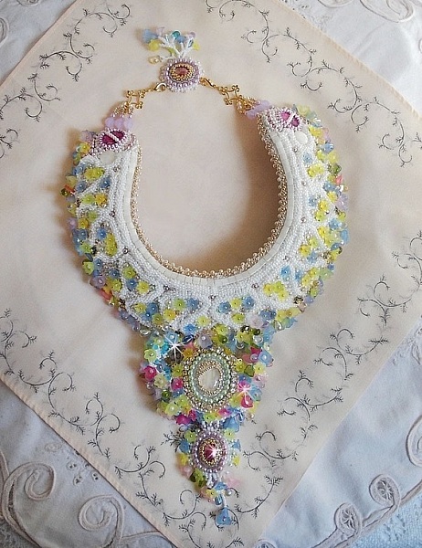 Plastron Envol&eacute;e Fleurie Haute Couture brod&eacute; avec des cabochons Nacre et R&eacute;sine aux couleurs Fuchsia et Ivoire, s&rsquo;ajoute des fleurs lucites, feuilles en verre, chatons et perles en Cristal.
